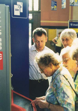 Seniorin bedient einen Fahrkartenautomaten mit Touchscreen