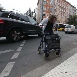 Auto biegt hinter einer Fußgängerin mit Rollator ab