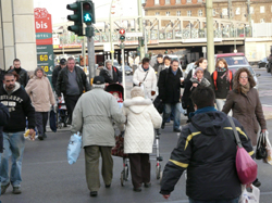 Junge und ältere Fußgänger überqueren eine Straße bei grüner Anmpelschaltung Junge und ältere Fußgänger überqueren eine Straße bei grüner Anmpelschaltung