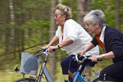 Zwei Seniorinnen fahren mit dem Fahrrad um die Wette.