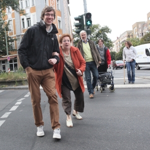 Foto: Carola Martin, Rheinsberg Junger Mann hilft einer älteren Frau über die Straße